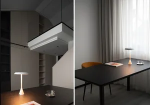 A modern home office setup featuring a wooden desk and chair, with curtains and a lamp illuminating the space.