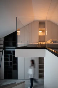 A modern minimalist bedroom featuring white walls, a black loft bed, and glass partitions.