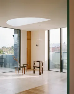 Minimalist residential interior featuring glass walls, wood furniture, and concrete flooring.