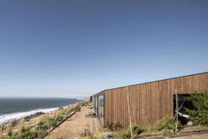 A modern modular coastal house with wooden exterior and ocean view.