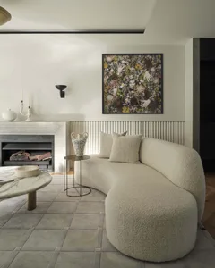A modern living room with curved sofa, fireplace, and abstract floral art.
