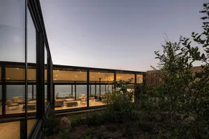 A modern residential interior featuring glass walls and wooden flooring.