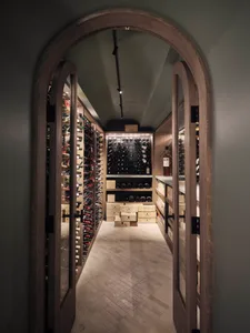 Modern wine cellar featuring wooden shelves and glass-enclosed wine racks.