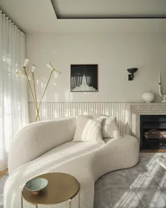 A minimalist living room with a curved sofa upholstered in textured fabric next to a fireplace with white curtains and modern