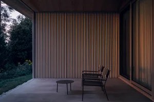 A minimalist porch with a metal frame and a round table.