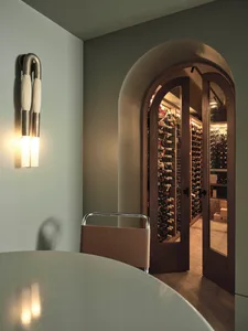 A minimalist wine cellar entrance featuring arched wooden doors and a curved wooden table.