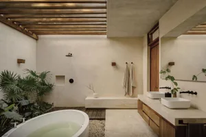 A modern bathroom with concrete walls, a freestanding bathtub, and natural light.