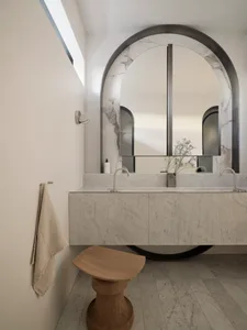 Modern bathroom with marble walls, a floating vanity, and an arched mirror.