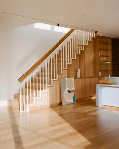 Modern interior design featuring wooden flooring and stairs with white railings.