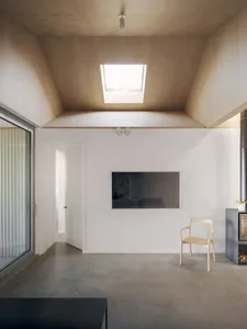 Minimalist living room with concrete floor, white walls, and a skylight.