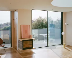 A modern living room featuring glass windows and wooden flooring.