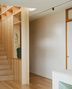 A minimalist staircase with a built-in bookshelf displaying a vase with flowers.