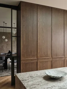 Modern residential interior with dark wood cabinets, marble countertop, and glass sliding door.