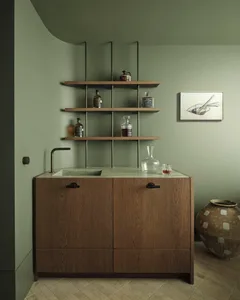 A minimalist bar station with wooden cabinets and shelves holding bottles of whiskey.