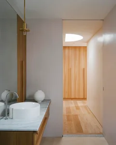 A minimalist bathroom with white porcelain sinks and natural wood elements.