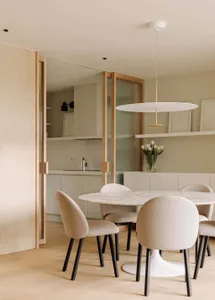 Modern minimalist kitchen with a glass table and upholstered chairs.