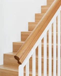 A modern staircase with a white handrail and wooden steps.