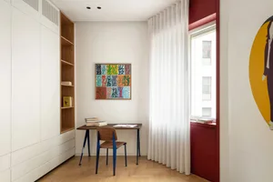 A minimalist home office featuring a wooden desk, chair, and white walls.