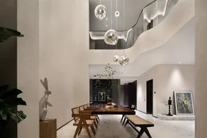 A modern minimalist dining room featuring a wooden table and chairs, with a contemporary light fixture and minimalist decor.