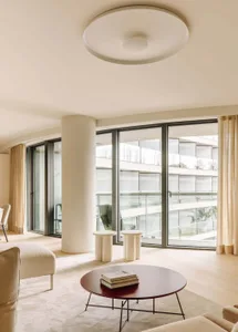 A modern living room with neutral-toned decor and large windows.