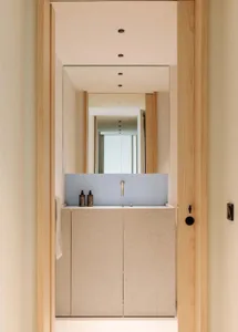 Modern minimalist bathroom with concrete vanity, white walls, and a large mirror.
