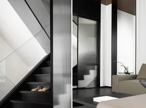 A modern living room with glass walls and black wooden flooring.