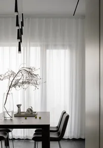 Modern minimalist dining room featuring a dark wooden table, black leather chairs, and minimalistic decor.