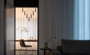 A minimalist living room features neutral-toned textiles, modern furniture, and a calm, curated atmosphere.