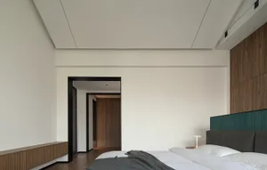 A modern minimalist bedroom with white walls, featuring a bed with a minimalistic headboard and a wooden floor.