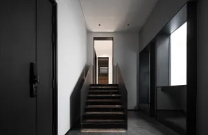 Modern minimalist staircase with black marble steps and black walls.