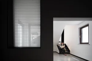 A minimalist modern residential interior with white concrete flooring, white walls, and large glass windows.