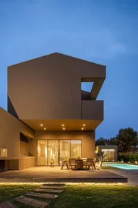 Modern house exterior with wood, concrete, and glass materials at dusk.