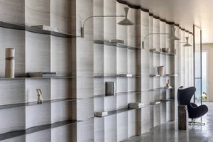 A minimalist library interior featuring curved, marble shelves and concrete columns.