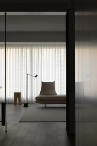 Modern minimalist living room with taupe sofa and curtains, featuring soft and comfortable furnishings.