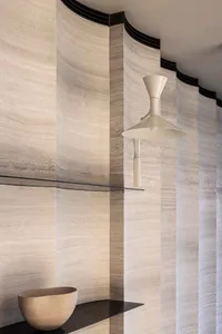 A beautifully designed modern bathroom with marble walls and floor tiles, featuring a sleek glass shelf and contemporary ligh