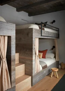 Modern bedroom featuring a wooden bunk bed with stairs leading to the top bunk and a cozy sleeping area with pillows and blan