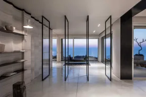 Modern residential entrance featuring glass walls, concrete floor, and metal railings.