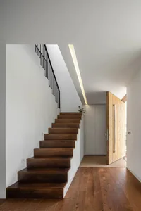 Modern interior design featuring wooden stairs with black railings and a wooden door.