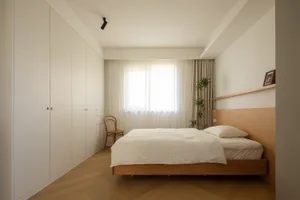 A modern minimalist bedroom featuring a wooden bed and furniture, with a large window and a white wall.