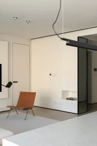A modern minimalist living room with a concrete floor and a single brown leather chair.