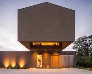 A modern residential building with a concrete exterior and warm indoor lighting.
