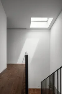 Modern staircase with white walls and wooden flooring, featuring a skylight.