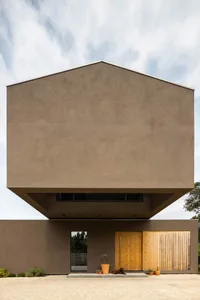 Modern house with stucco facade, concrete roof, and wooden door and window frames.