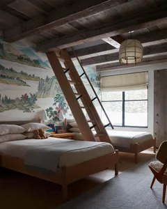 A rustic, industrial-style bedroom featuring wooden furniture and a mural of mountain landscapes on the wall.