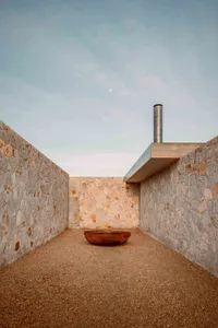 極簡建築空間，設有混凝土走道搭配礫石地面，散發優雅與簡約氛圍。