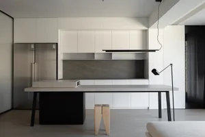 A minimalist kitchen featuring concrete finishes and white cabinetry.