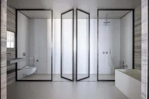 Modern industrial bathroom featuring glass walls and minimalistic design.