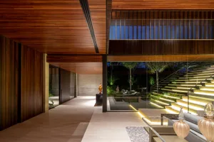A modern interior living room with glass stairs leading to an outdoor area, featuring soft lighting and minimalist decor.