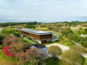 A modern residential home featuring glass walls, wooden accents, and concrete patio.