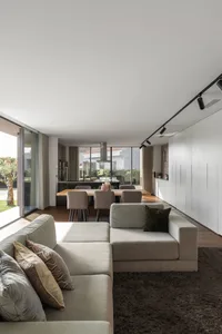 A modern living room with a beige sectional sofa, throw pillows, and a brown rug.